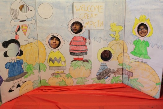 Club members created a Peanuts Great Pumpkin scene with cut outs for their faces. The club members' faces are inside the cut outs.