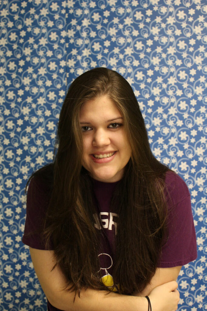 Bethany in a burdundy t-shirt against a blue and white star pattern background.