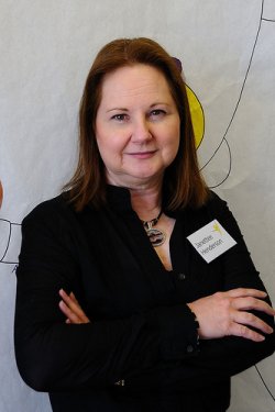 Janettee with brown hair, black blouse, and decorative necklace.