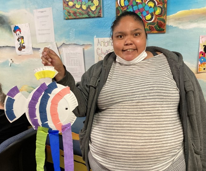 Participant holding the fish mobile she created from paper plate, cupcake liners, and crepe paper streamers.